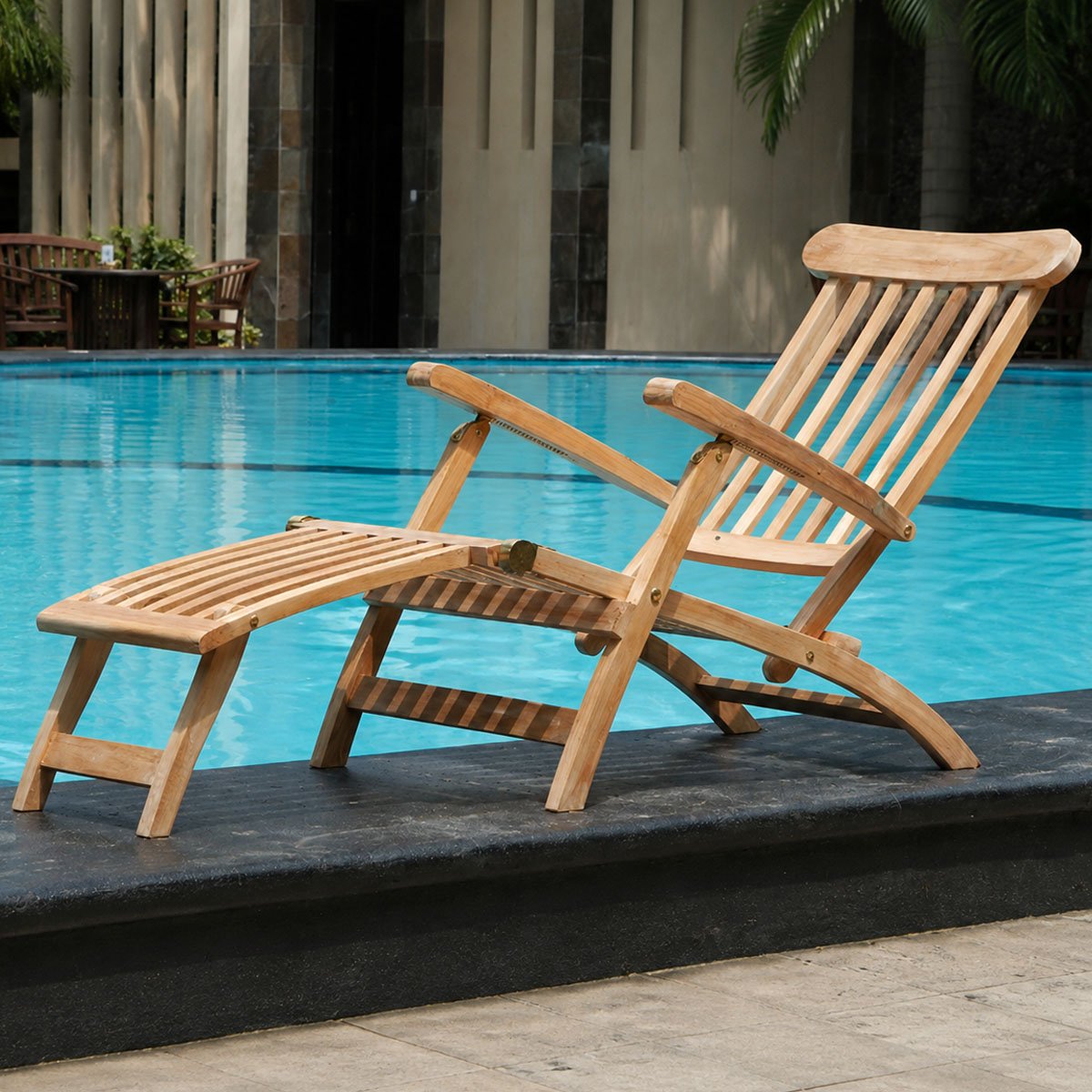 Indonesian teak adjustable sun lounger with footrest beside a swimming pool